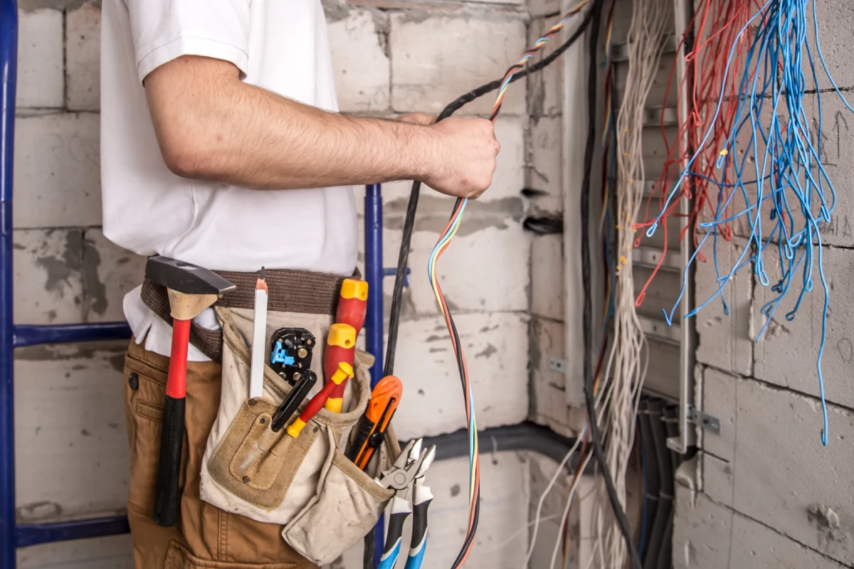 Inštalácia elektrických rozvodov a revízne meranie; elektrikár pri kontrole rozvádzača.